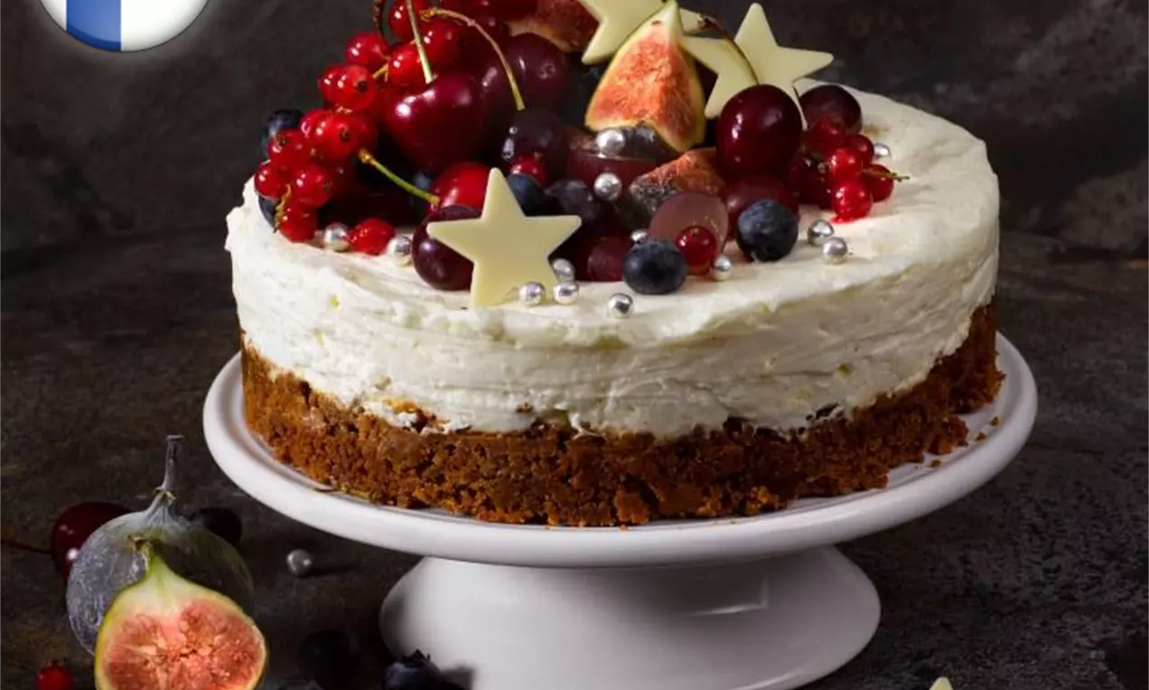 Prăjitură cu blat brun și cremă albă de mascarpone, decorată cu fructe de pădure, smochine, perle argintii și stele de ciocolată pe un platou alb