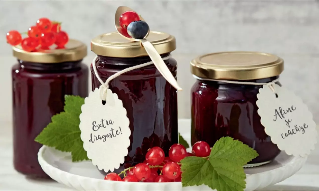 Dulceață densă și lucioasă de un vișiniu profund în borcane elegante, decorată cu etichete albe și crenguțe de frunze și fructe